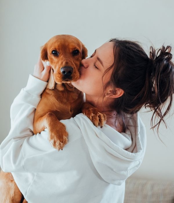Woman kissing her dog affectionately while holding it close