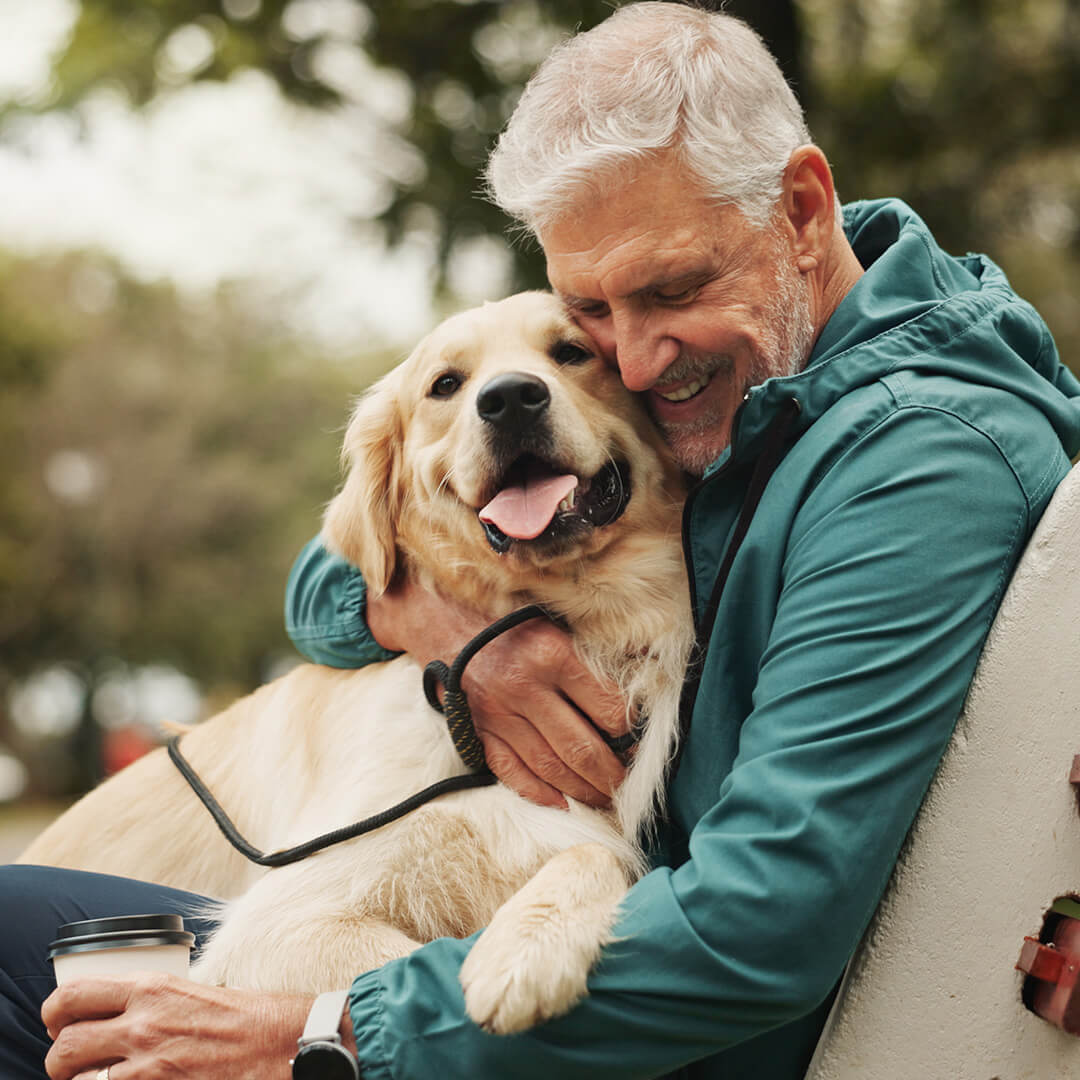 Elderly man hugging a golden retriever