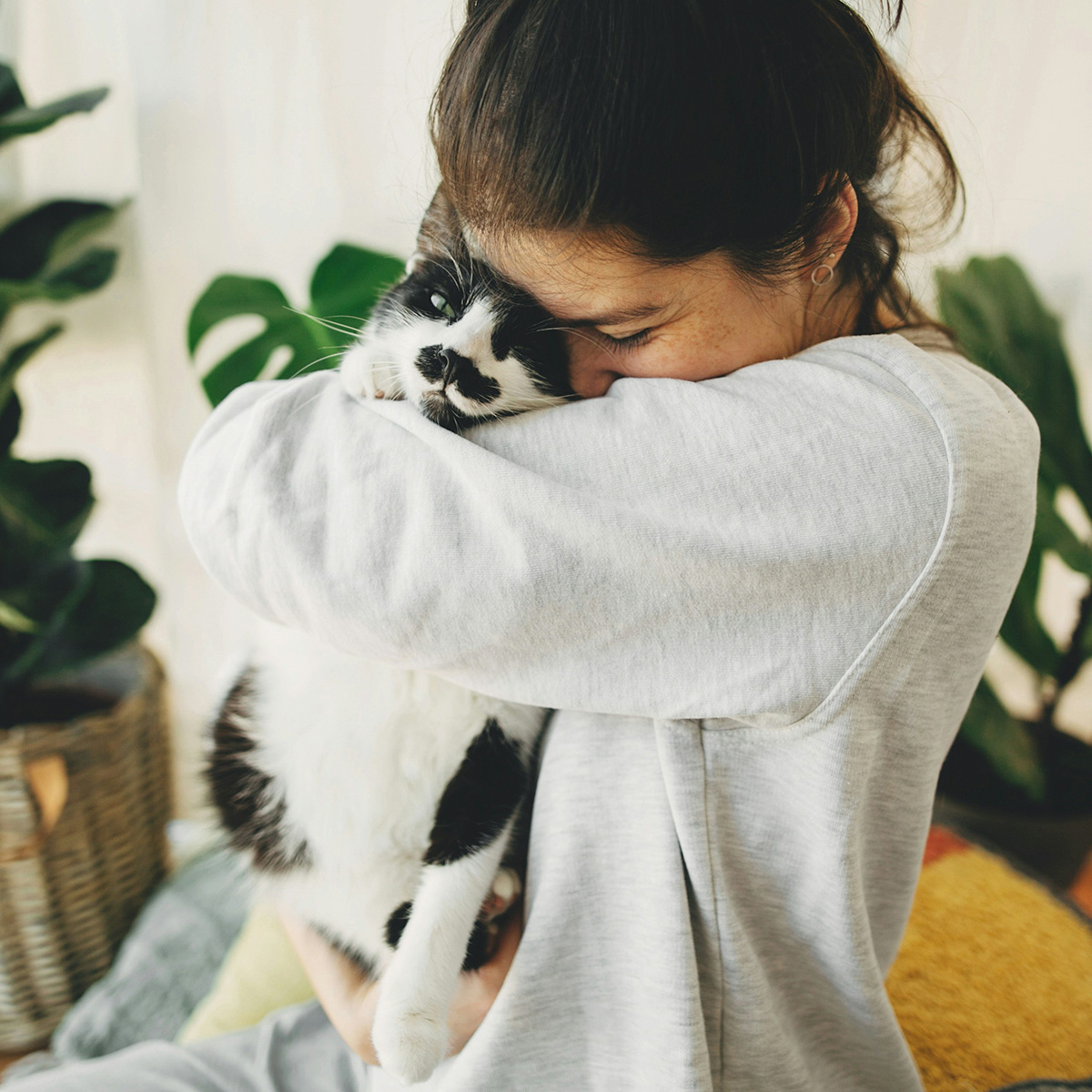 Woman hugging black and white cat